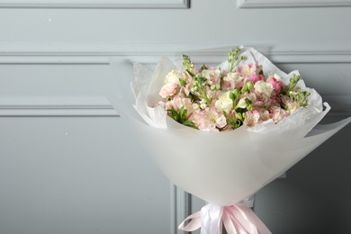 Photo of Beautiful bouquet of fresh flowers near grey wall, space for text