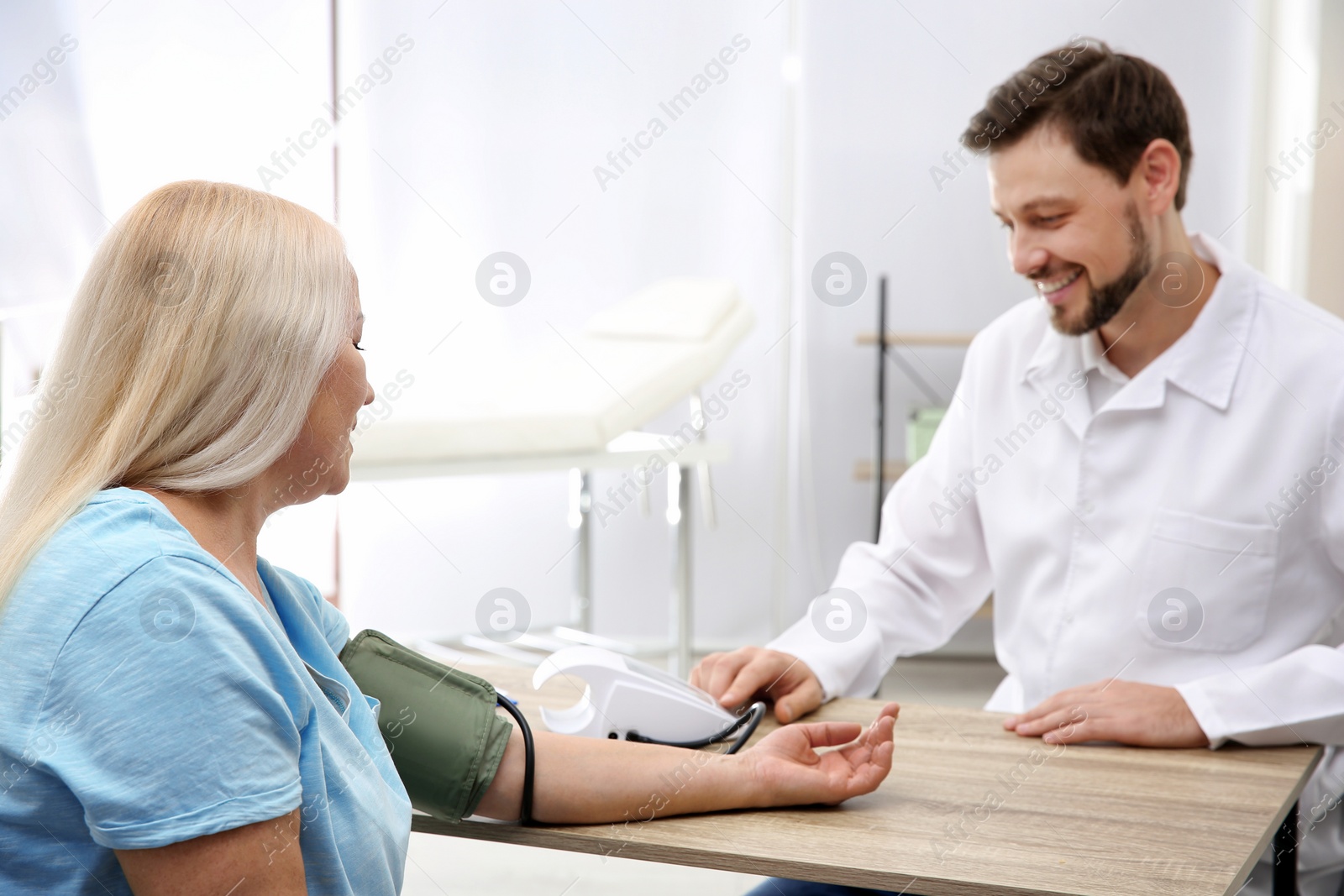 Photo of Doctor checking mature woman's pulse with medical device in hospital