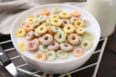 Photo of Cereal rings and milk in bowl on table, closeup