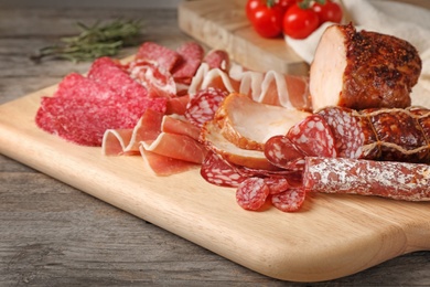 Photo of Cutting board with different meat delicacies on wooden table