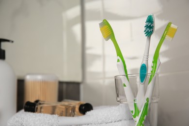 Light blue and green toothbrushes in glass holder indoors, space for text