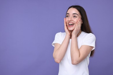 Portrait of happy surprised woman on violet background. Space for text