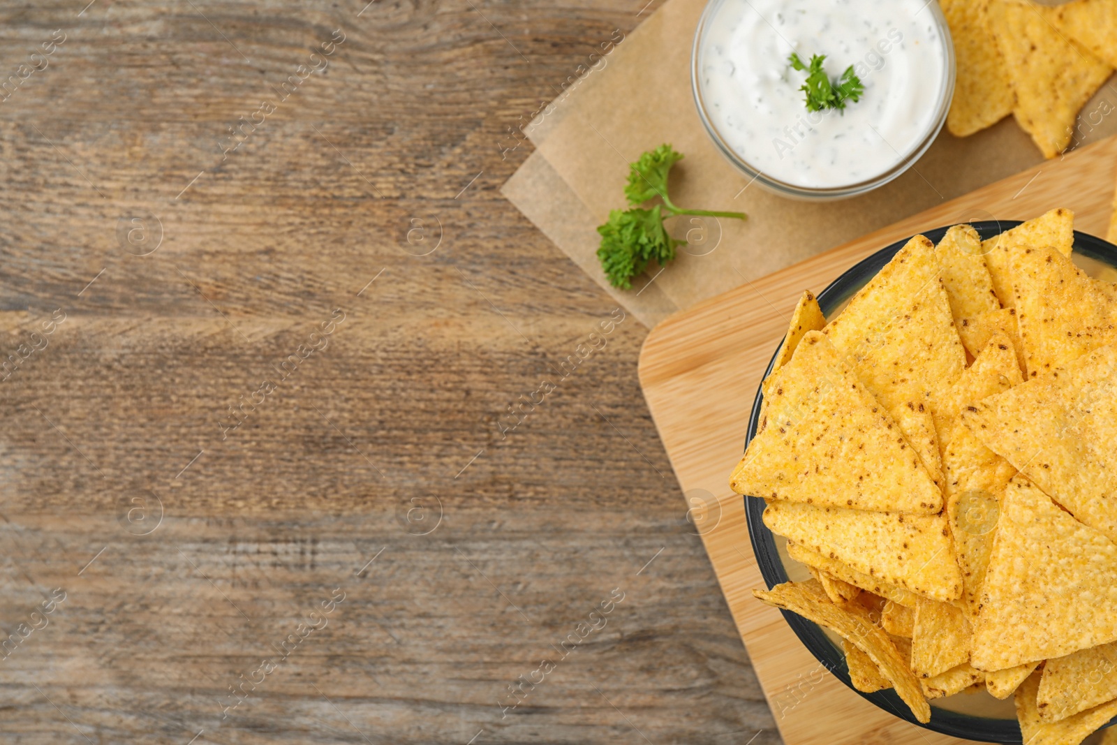 Photo of Mexican nacho chips with sauce on wooden background, flat lay. Space for text