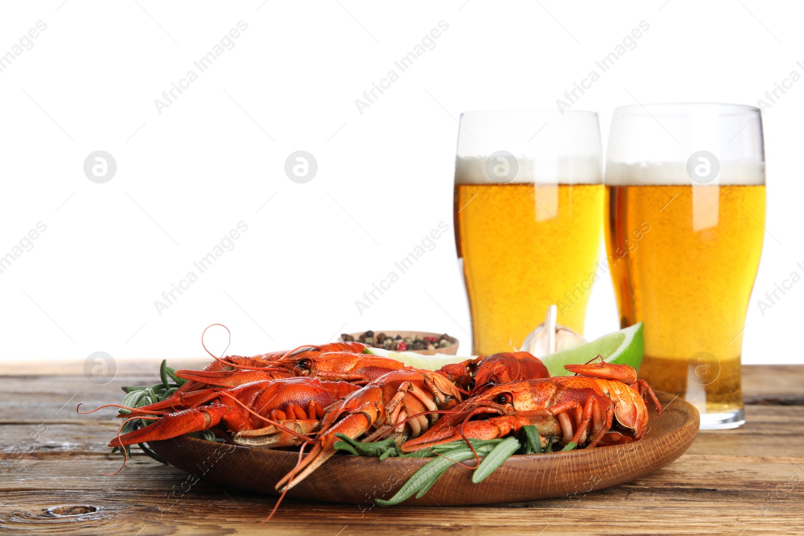 Photo of Delicious red boiled crayfishes and beer on wooden table against white background