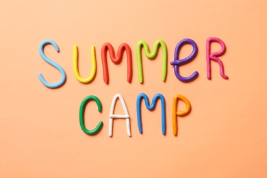 Text SUMMER CAMP made of modelling clay on color background, flat lay