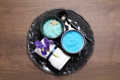 Light blue sea salt in bowls, flower, towel and starfish on wooden table, top view