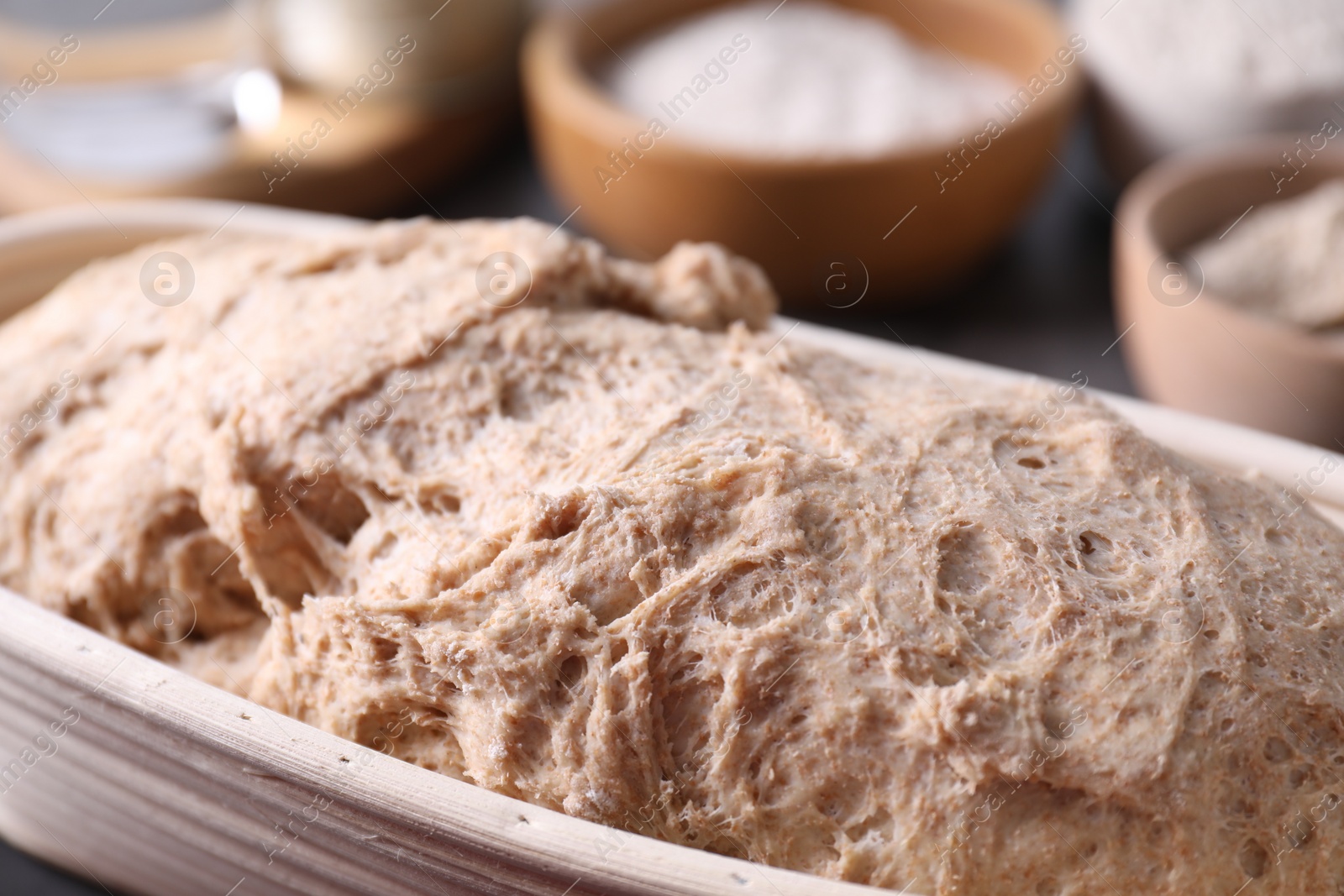 Photo of Fresh sourdough in proofing basket on table, closeup