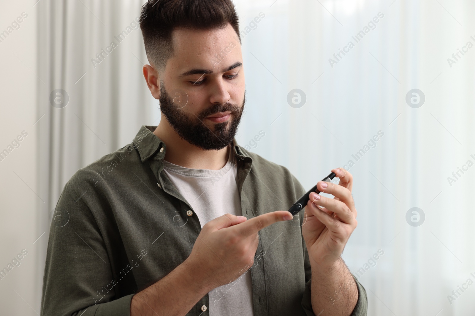 Photo of Diabetes test. Man checking blood sugar level with lancet pen at home