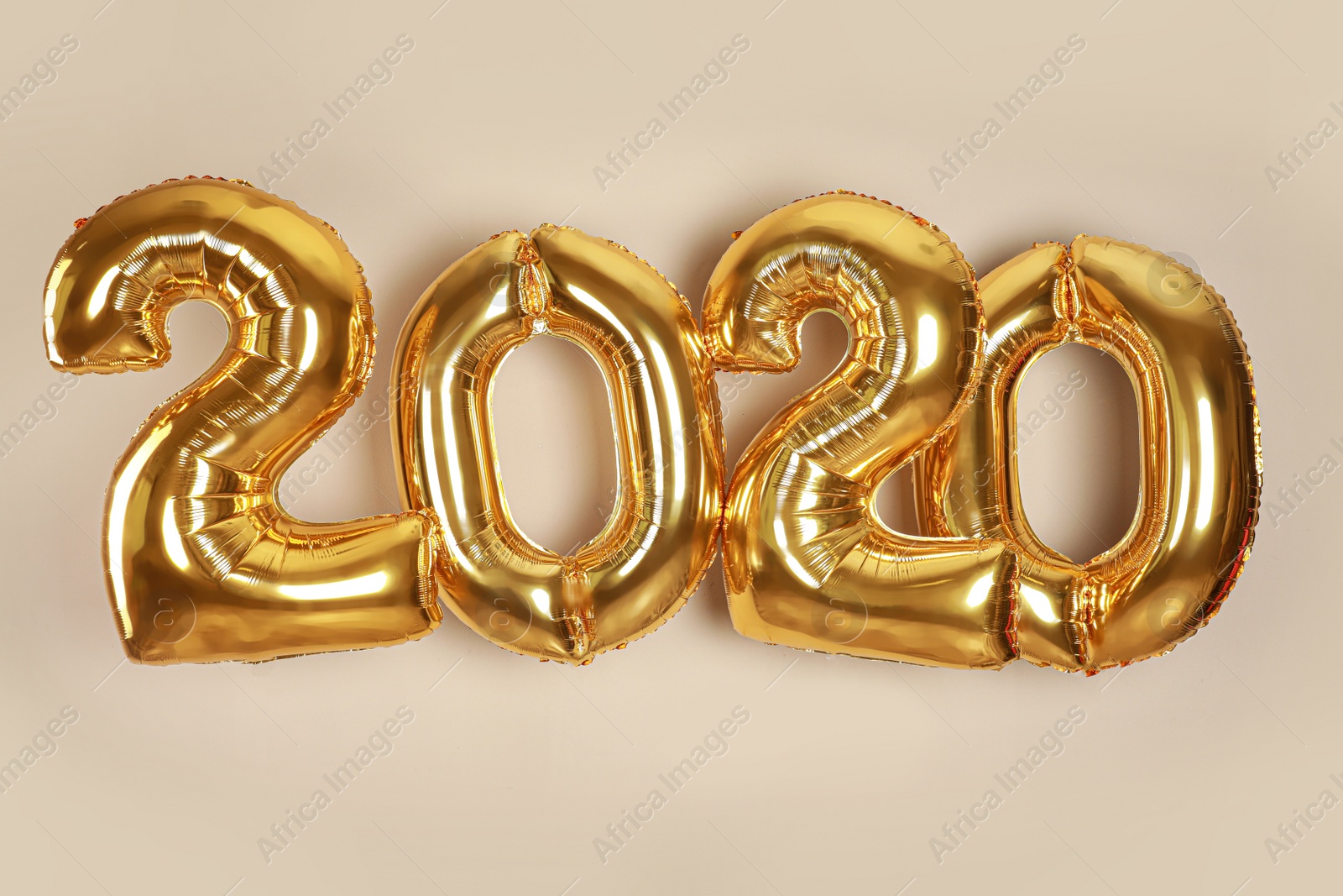 Photo of Golden balloons for party decoration on beige background. 2020 New Year celebration