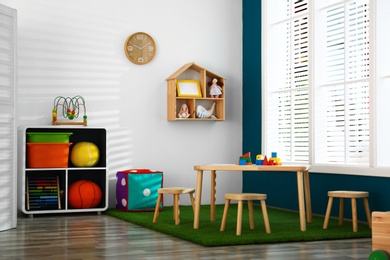 Photo of Stylish playroom interior with wooden table and stools