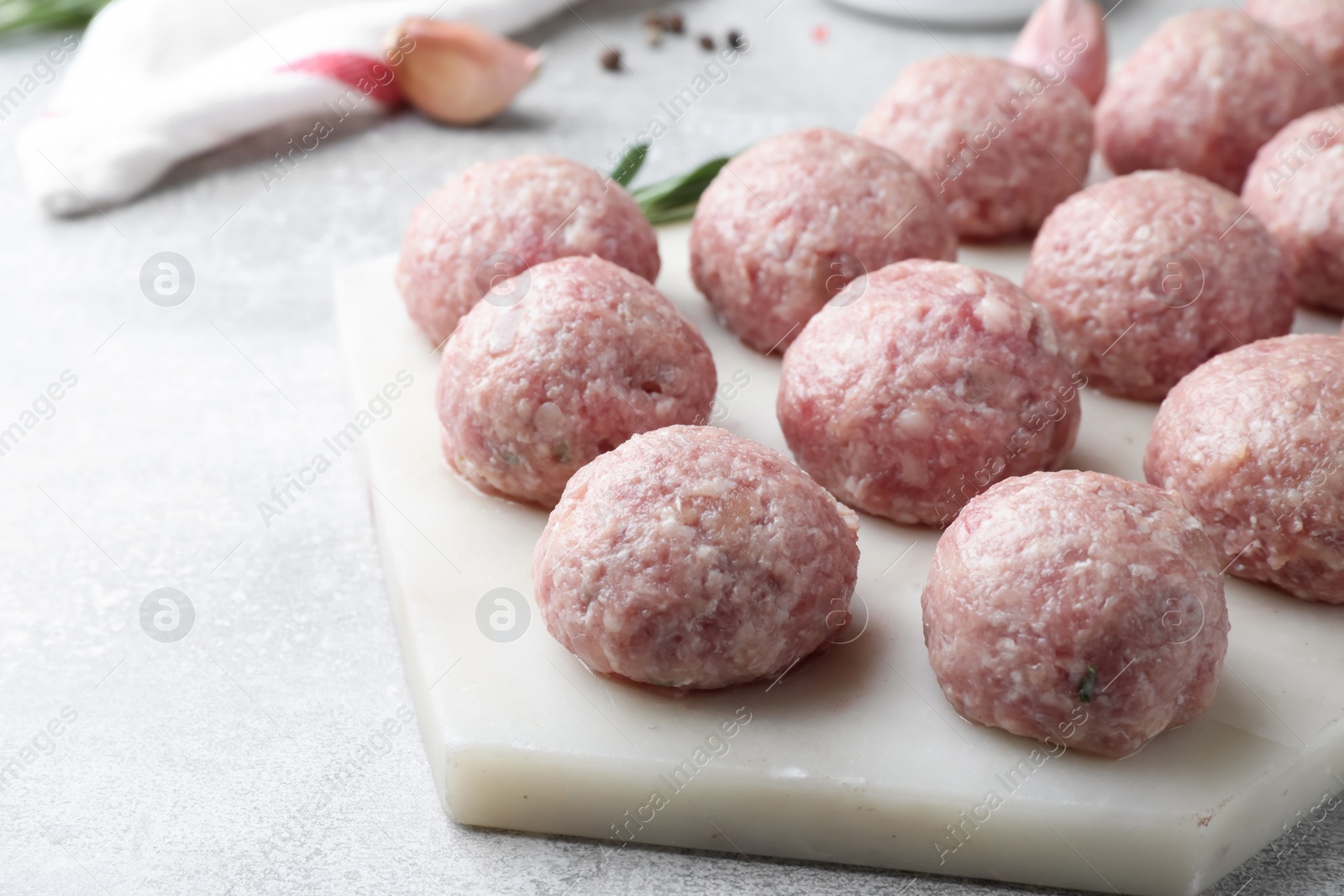 Photo of Many fresh raw meatballs on light grey table, closeup