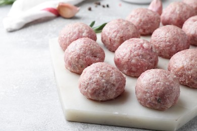 Photo of Many fresh raw meatballs on light grey table, closeup