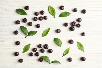 Photo of Flat lay composition with fresh acai berries and leaves on wooden background