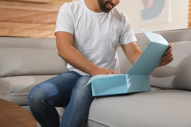 Photo of Man unpacking parcel at home, closeup. Online shopping