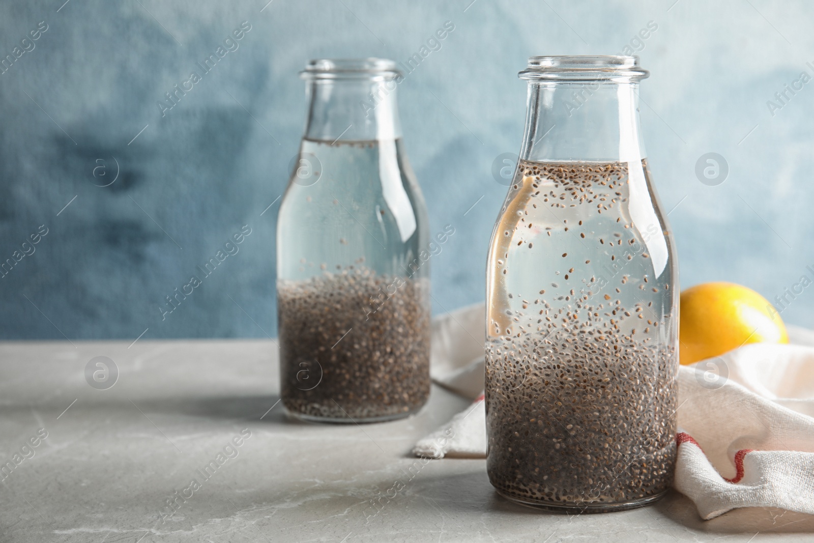 Photo of Composition with bottles of water and chia seeds on table against color background. Space for text