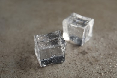 Ice cubes with water drops on grey stone table, closeup