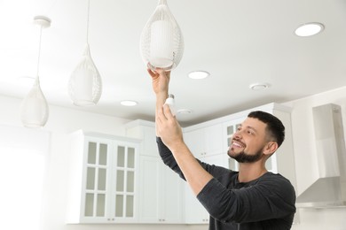 Photo of Man changing light bulb in lamp at home. Space for text