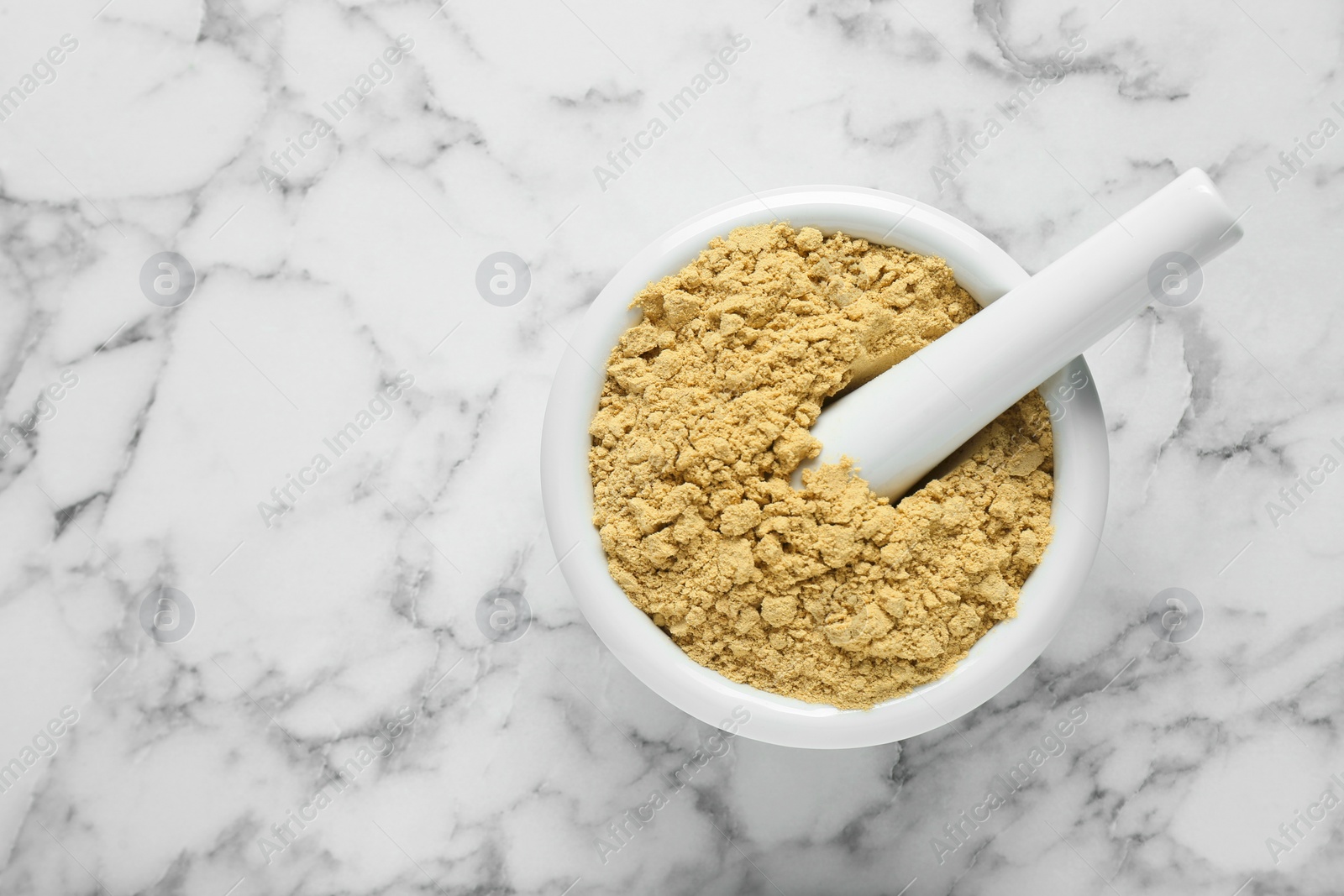 Photo of Mortar with aromatic mustard powder on white marble table, top view. Space for text