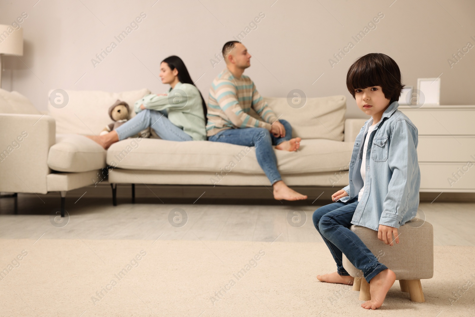 Photo of Sad couple with relationship problems at home, focus on their upset child