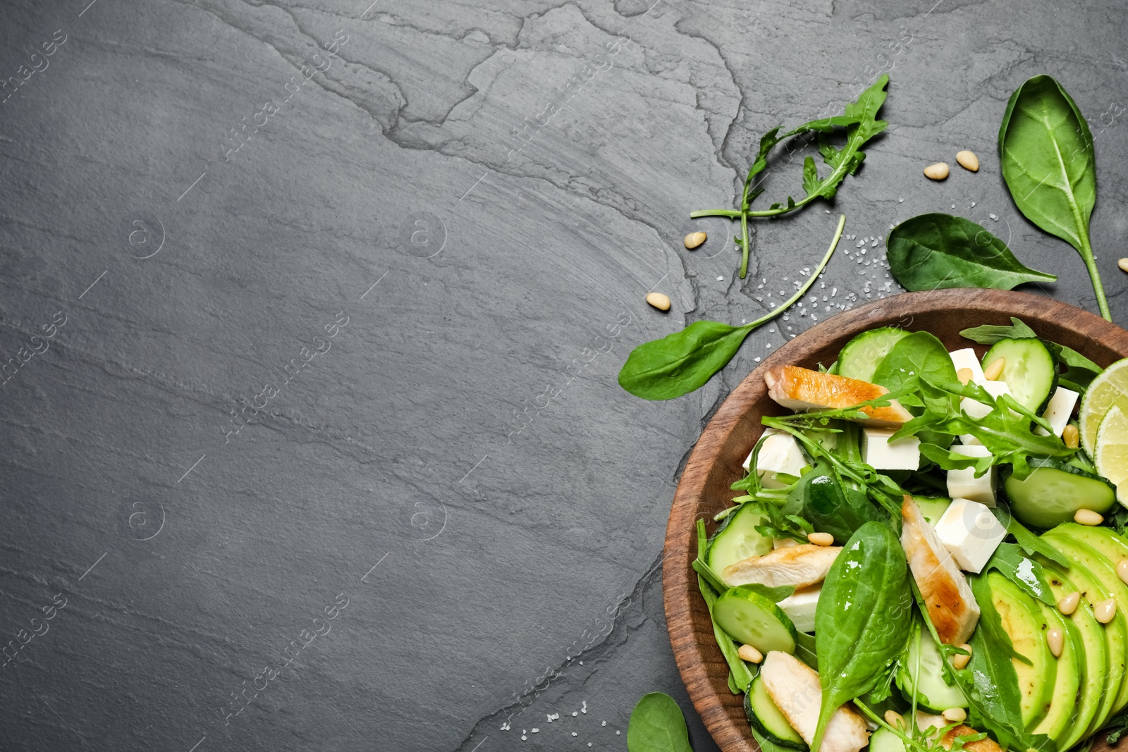 Photo of Delicious salad with chicken, arugula and avocado on black table, flat lay. Space for text