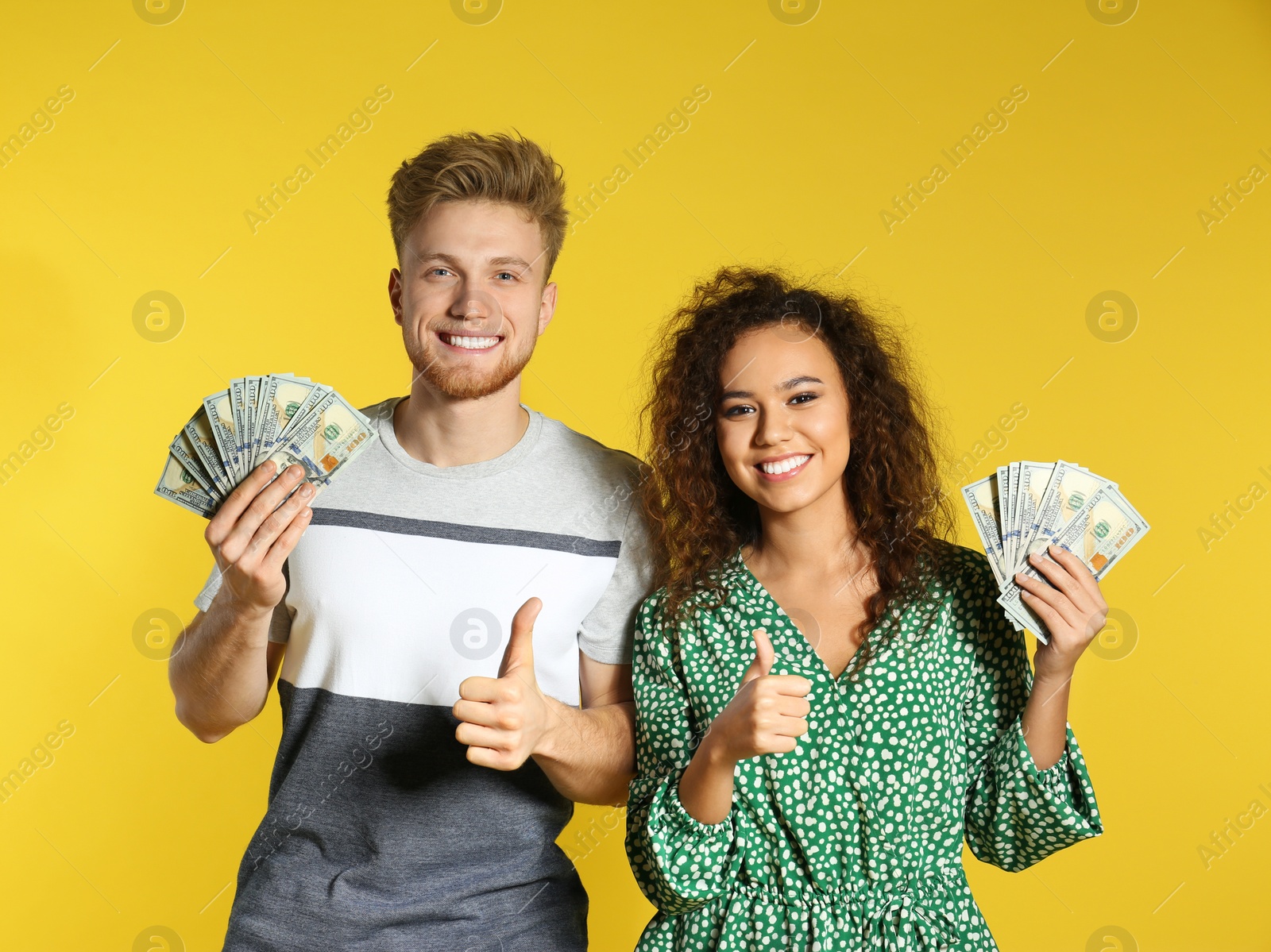 Photo of Young couple with money on color background