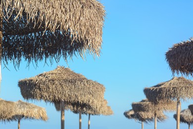 Beautiful straw beach umbrellas against blue sky