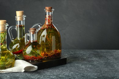 Photo of Cooking oil with different spices and herbs in jugs on light grey table. Space for text