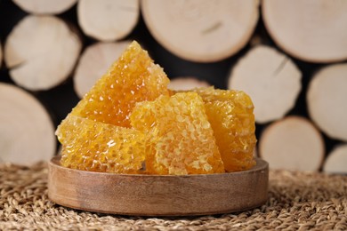 Photo of Natural honeycombs on wicker mat near woods, closeup