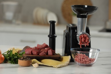 Electric meat grinder with beef mince and products on white table against blurred background, closeup