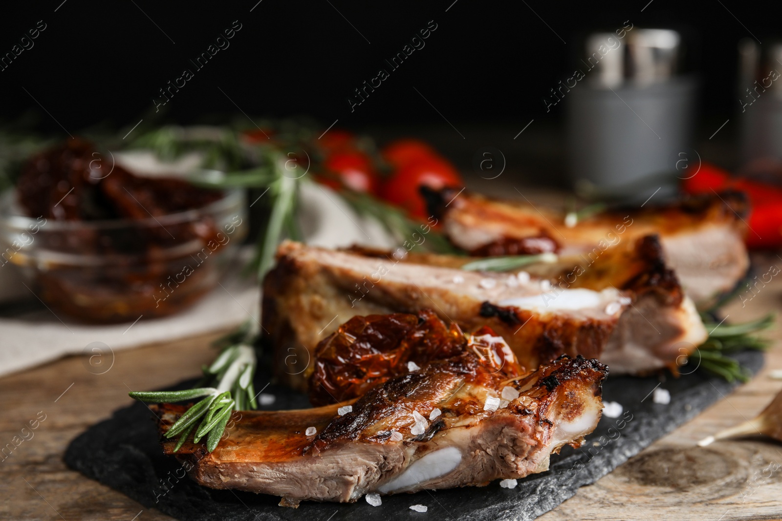 Photo of Tasty grilled ribs with rosemary on wooden table, closeup