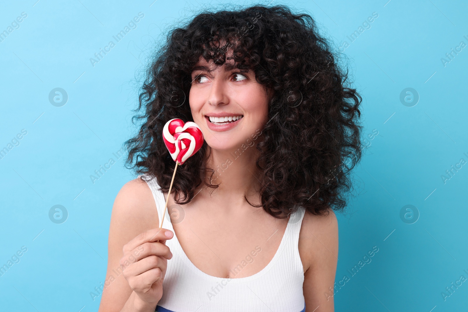 Photo of Beautiful woman with lollipop on light blue background