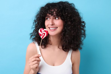 Beautiful woman with lollipop on light blue background