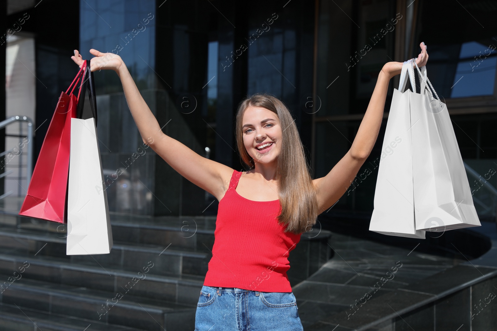 Photo of Happy young woman with shopping bags outdoors