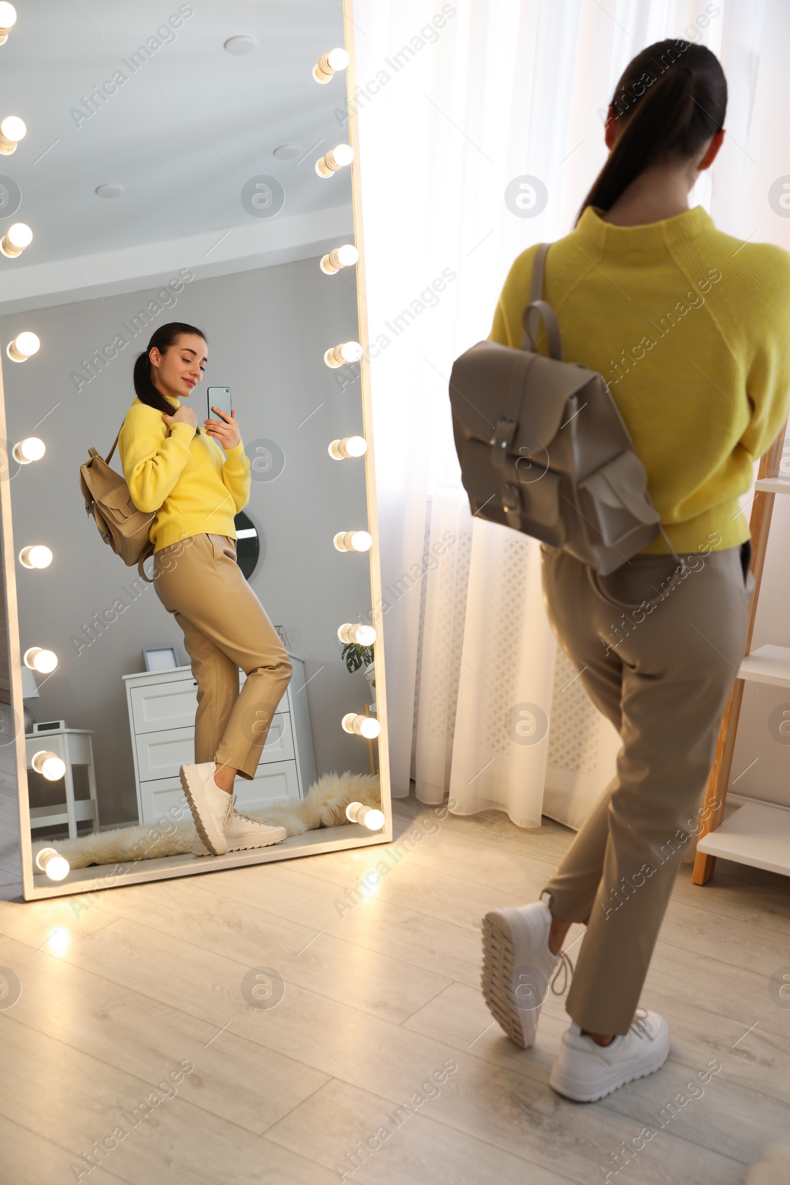 Photo of Young woman taking mirror selfie in stylish outfit at home. Morning routine