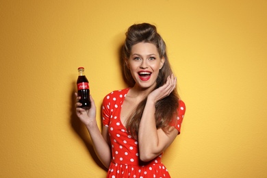 Photo of MYKOLAIV, UKRAINE - NOVEMBER 28, 2018: Young woman with bottle of Coca-Cola on color background