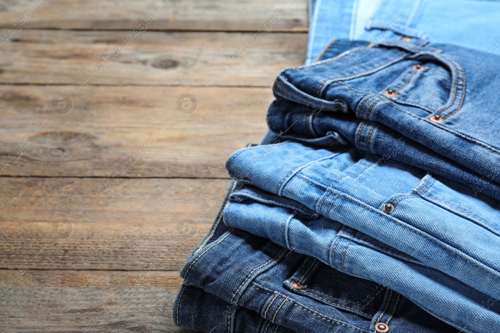 Photo of Collection of stylish jeans on wooden background, closeup. Space for text