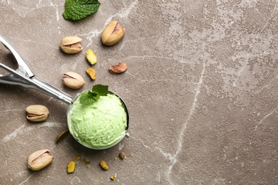 Photo of Scoop with tasty pistachio ice cream on grey table, flat lay. Space for text