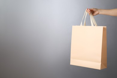 Photo of Woman holding paper bag on grey background, closeup with space for text. Mockup for design