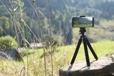 Photo of Taking photo of beautiful mountain landscape with smartphone mounted on tripod outdoors, space for text