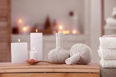 Photo of Spa composition with burning candles and herbal bags on massage table in wellness center