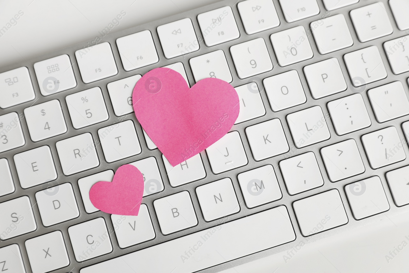 Photo of Keyboard with pink hearts on white table, top view. Valentine's day celebration