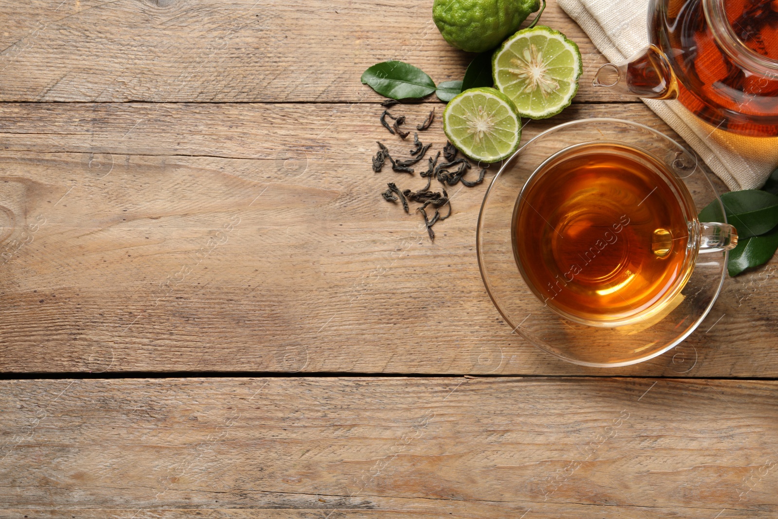 Photo of Glass cup of tasty bergamot tea and fresh fruits on wooden table, flat lay. Space for text