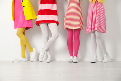 Photo of Women wearing colorful tights near white wall, closeup