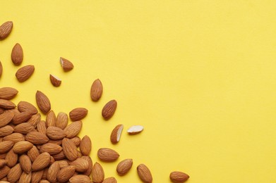 Delicious raw almonds on yellow background, flat lay. Space for text