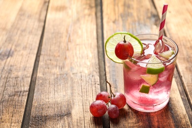 Photo of Soda water with grapes, ice and lime on wooden table, space for text. Refreshing drink