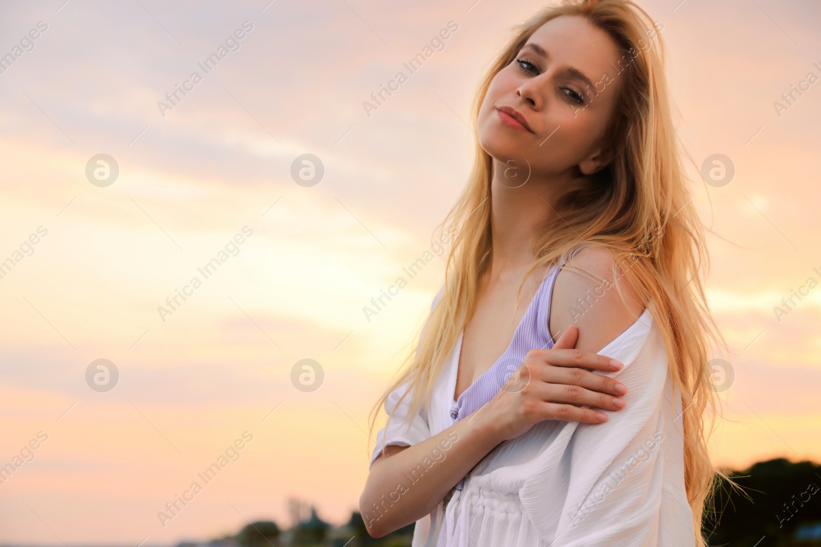 Photo of Beautiful young woman outdoors at sunset, space for text