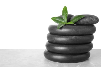 Photo of Stack of spa stones and green leaves on table against white background. Space for text