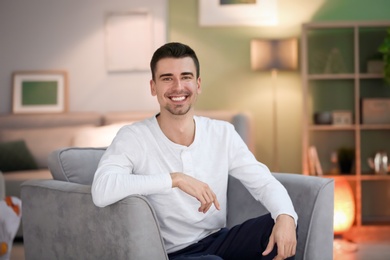 Photo of Young man sitting in armchair at home