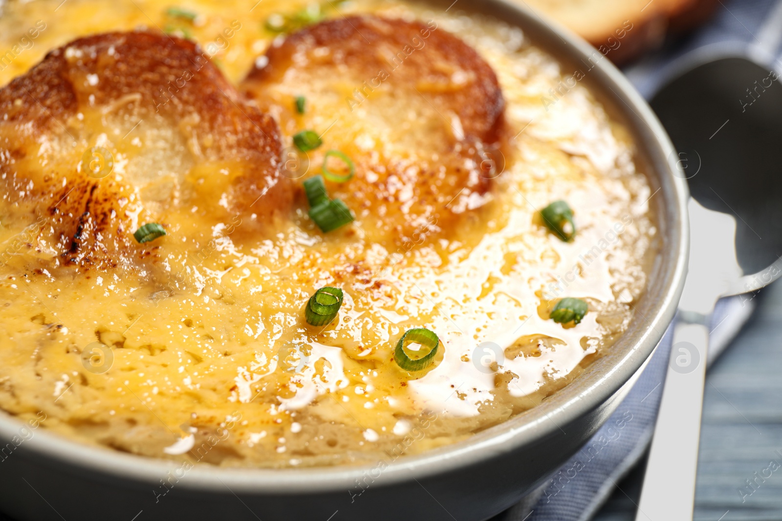 Photo of Tasty homemade french onion soup served in ceramic bowl, closeup