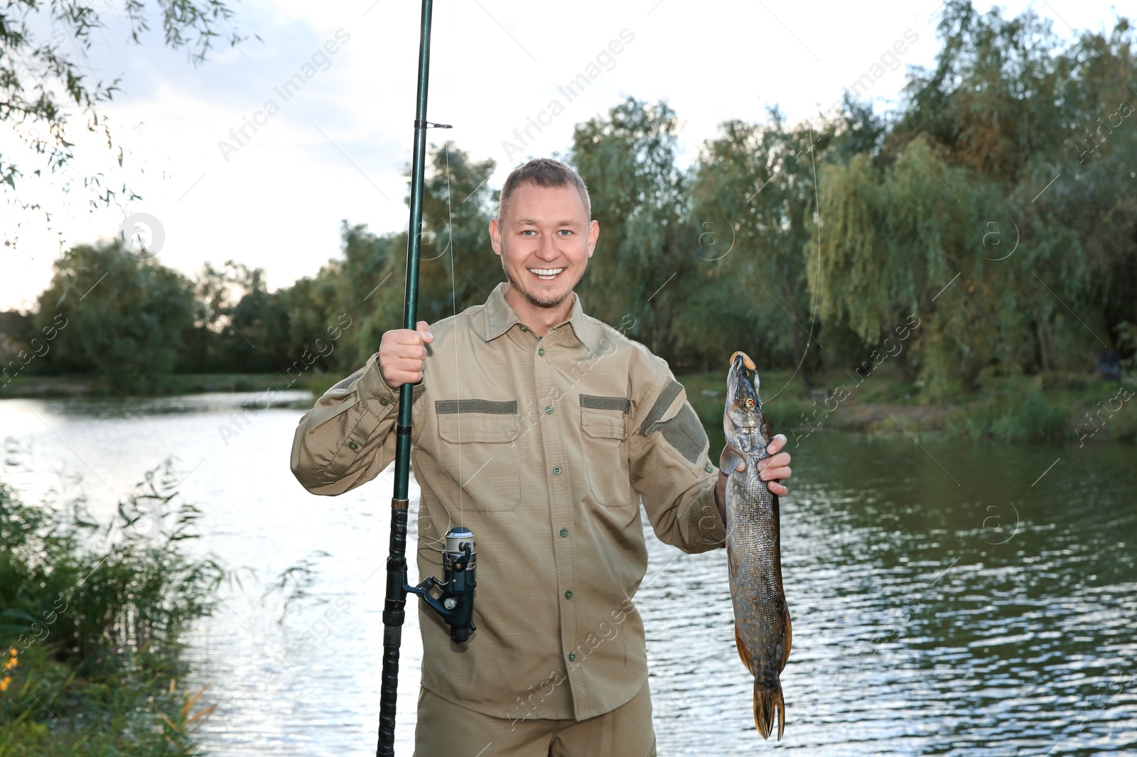 Photo of Man with rod and catch fishing at riverside. Recreational activity